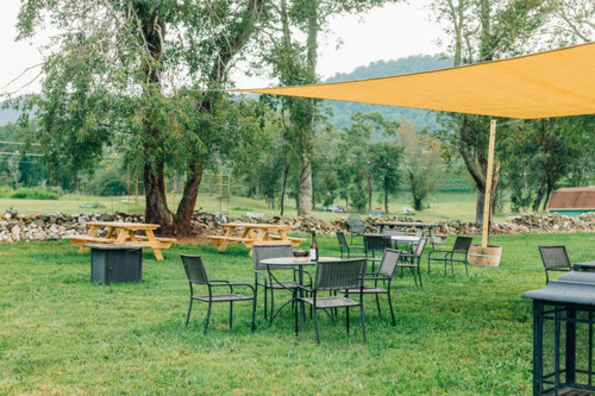 The picnic area set up with cafe tables under a golden shade sail, ready for a small gathering