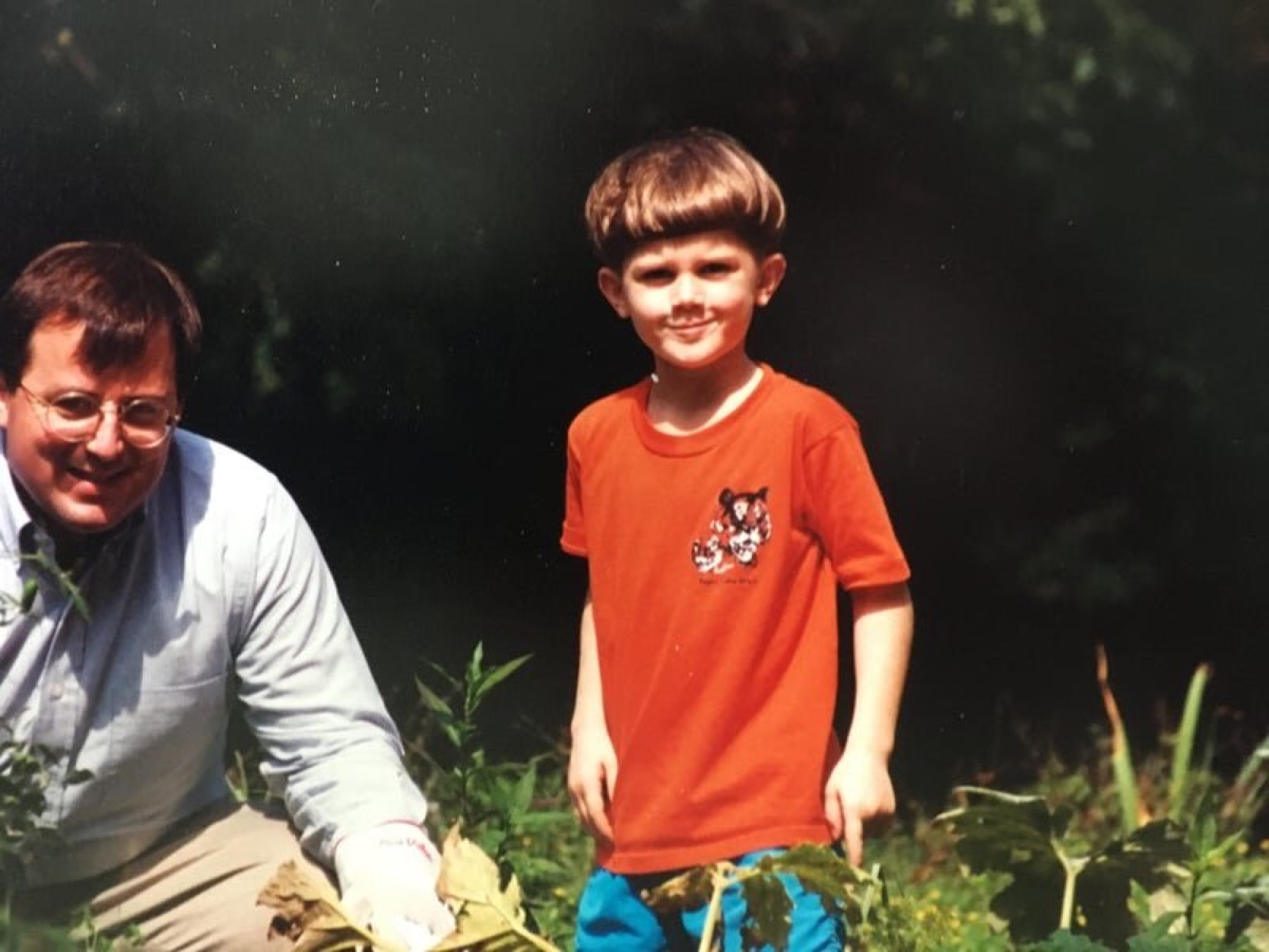 A father with a young child outdoors, both smiling, vintage photo